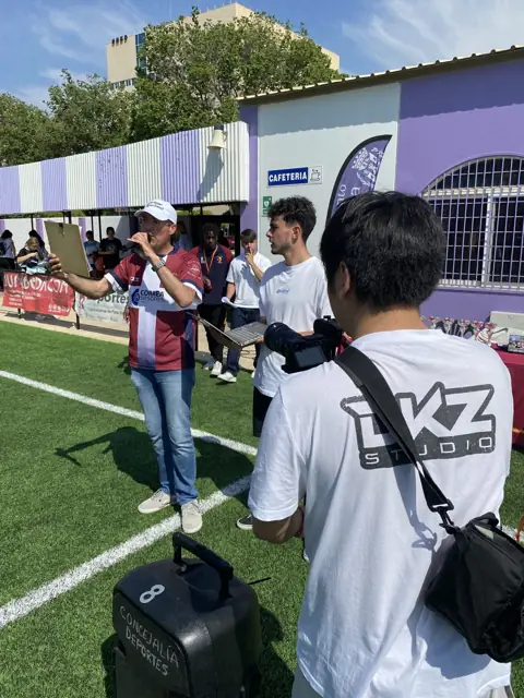 Fotógrafo de DKZ Studio cubriendo un torneo deportivo con cámara y bolsa de equipo · marketing y producción audiovisual para Torre Pacheco