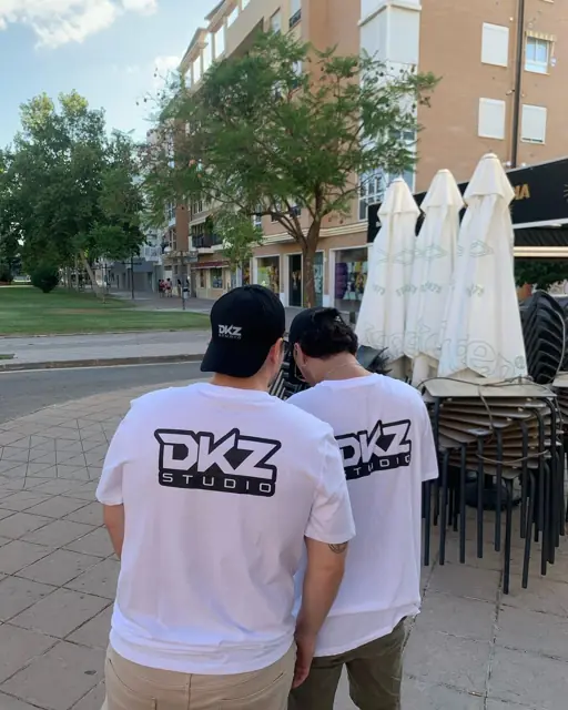Dos miembros de DKZ Studio de espaldas en una plaza con terrazas preparando una grabación · DKZ Studio, Murcia