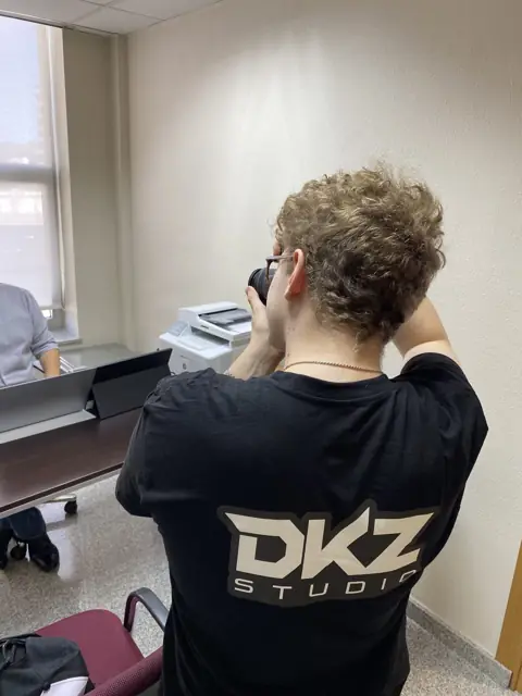 Fotógrafo de DKZ Studio con cámara trabajando en una sala de oficinas · marketing y producción audiovisual para Lorca
