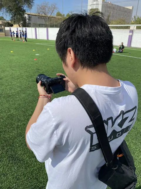 Fotógrafo de DKZ Studio con cámara en un campo de fútbol de césped artificial · marketing y producción audiovisual para Alcantarilla