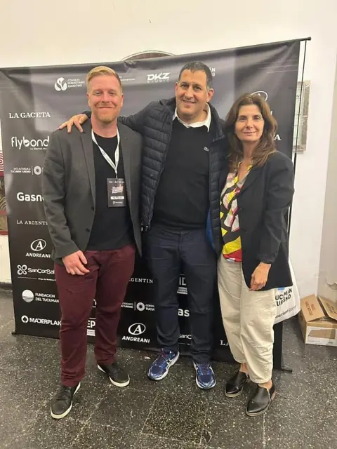 Tres asistentes posan ante un photocall con logos de patrocinadores en un evento profesional · DKZ Studio, Murcia