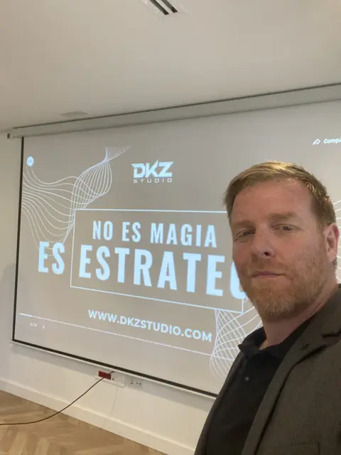 Pantalla con la frase «No es magia, es estrategia» y la web dkzstudio.com durante una charla de DKZ Studio · agencia de marketing y vídeo para negocios de Santiago y Zaraiche