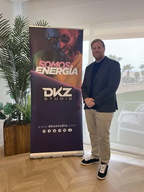 Roll-up de DKZ Studio con lema «Somos energía» junto a un ponente en una sala de conferencias · agencia de marketing y vídeo para negocios de Algezares