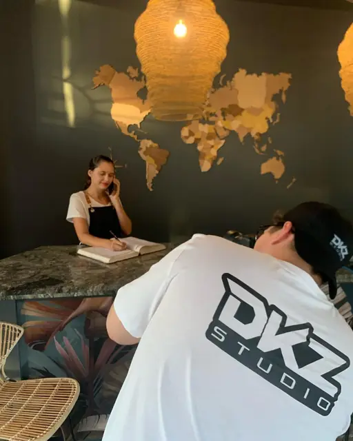 Miembro de DKZ Studio grabando en la recepción de un local con mapamundi de madera · DKZ Studio, Murcia