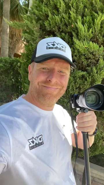 DKZ Studio videographer with a professional camera on a monopod and studio cap · marketing and video agency for businesses in La Manga